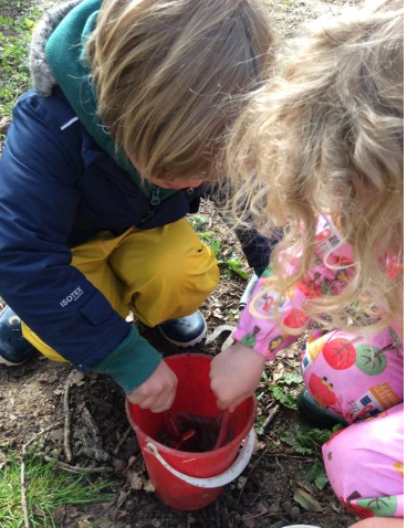 Children mixing mud in a bucket