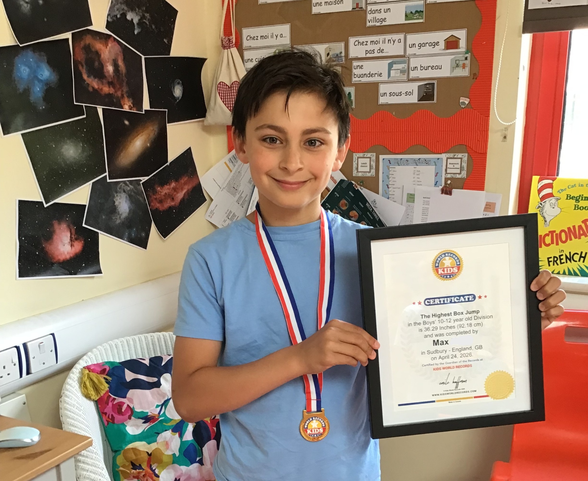 Max in the Year 5 classroom holding his certificate and wearing his medal