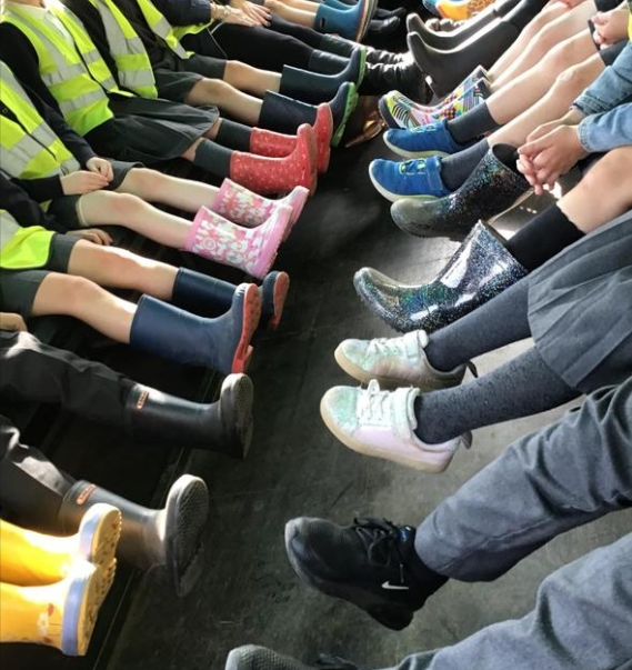 Children on a tractor's trailer ride showing their colourful welly boots