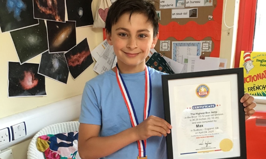 Max in the Year 5 classroom holding his certificate and wearing his medal