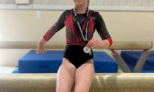 Alice sat on a vault apparatus presenting her gold medal