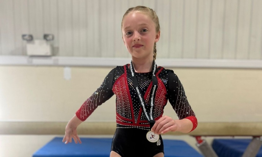 Alice sat on a vault apparatus presenting her gold medal