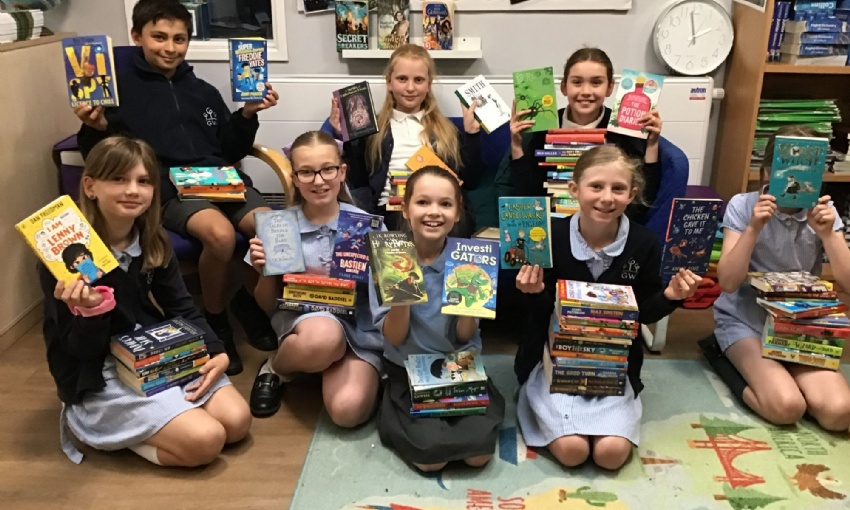 Year 5 children showing their books in the library